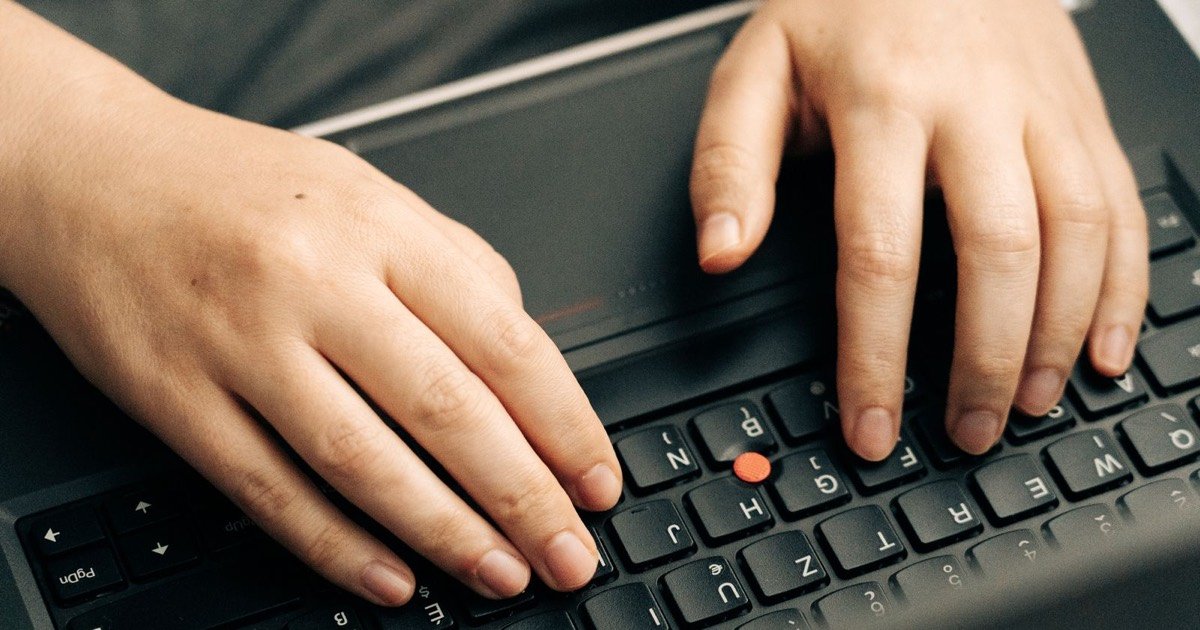 Hände tippen auf einer Laptop-Tastatur